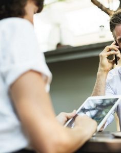 Two people at a table on mobile devices.