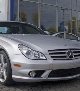 Silver Mercedes in front of a car dealership.